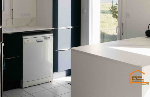 Une cuisine rénovée avec des lignes épurées et des matériaux élégants, offrant un espace pratique et baigné de lumière naturelle.