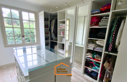 Pièce dressing lumineuse avec verrière centrale, rangements sur-mesure et vue sur jardin arboré en Haute-Savoie.