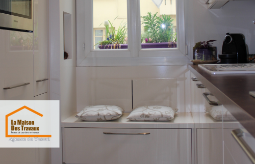 Rénovation d’une cuisine à Luxeuil : espace optimisé avec banc de rangement sous fenêtre et four encastré pour plus de praticité.