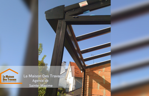 La charpente en aluminium est en cours de montage, préparant la pose des panneaux en verre pour une isolation optimale.  