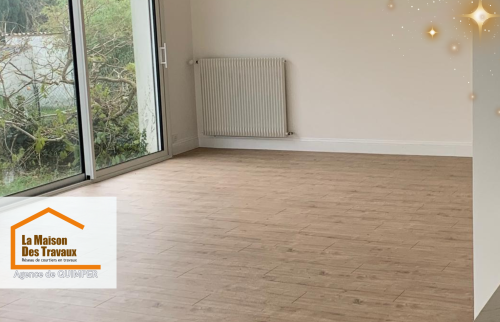 Le salon baigné de lumière naturelle grâce à de larges baies vitrées, sublimé par un parquet clair qui agrandit l’espace.