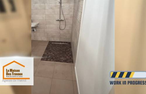 Vue d’ensemble de la douche sécurisée en cours de rénovation, avec carrelage mural texturé et espace large sans ressaut, adaptée PMR.
