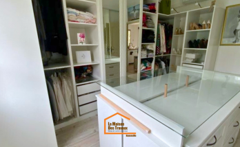 Dressing sur mesure avec îlot central vitré, rangements ouverts et penderies intégrées – aménagement intérieur en Haute-Savoie.