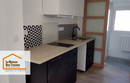 Rénovation de cuisine à Vesoul : Modernisation avec meubles noirs et blancs, crédence géométrique et plan de travail bois clair. Un projet signé La Maison Des Travaux Vesoul.