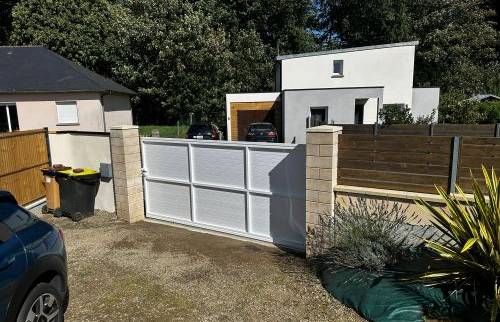 Vue d’ensemble de l’entrée après travaux, avec portail coulissant et clôture intégrés à l’environnement existant.