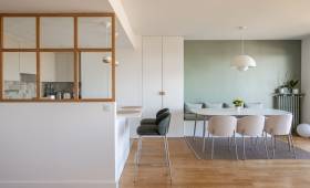 Table à manger blanche ovale et banquette contre un mur vert