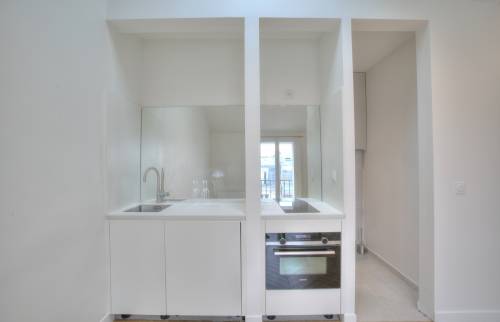 cuisine épurée ouverte sur la pièce de vie avec une crédence miroir