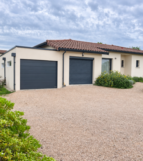 Garage en modules béton avec toit plat et porte anthracite, attenant à une maison à L’Isle-Jourdain. 