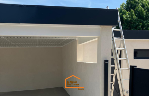 Construction d’un carport en Haute-Savoie avec structure maçonnée, toit plat moderne et finition noire – vue latérale avec échelle.