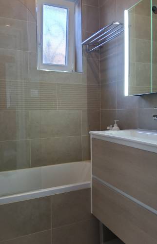 Zoom sur le carrelage couleur sable avec sa frise effet relief et le nouveau mobilier en bois clair à Courrières