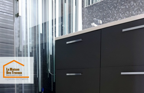 énovation élégante de salle de bain avec un meuble vasque suspendu au design moderne, une paroi de douche vitrée et un carrelage mosaïque noir hexagonal. 