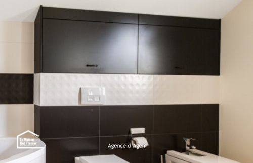 Salle de bain rénovée à Agen : sèche-serviettes noir, meuble vasque et baignoire d’angle pour plus de confort.