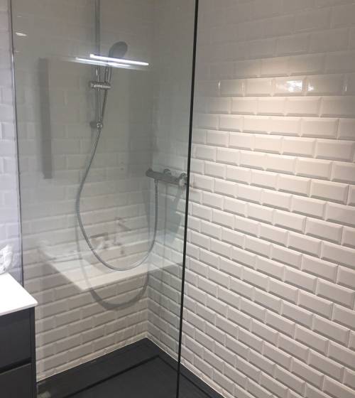 Douche rénovée avec carrelage métro blanc et colonne de douche moderne.