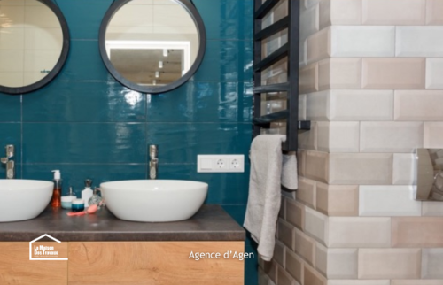 Rénovation de salle de bain à Agen avec double vasque, meuble en bois et carrelage bleu profond.