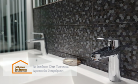 Un meuble sous-vasque suspendu moderne et pratique, avec un mur en carrelage mosaïque pour une touche élégante.