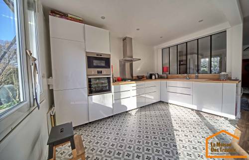 Rénovation de cuisine à Dourges style atelier : meubles blancs sans poignées, verrière noire, plan de travail en bois et sol en carreaux de ciment