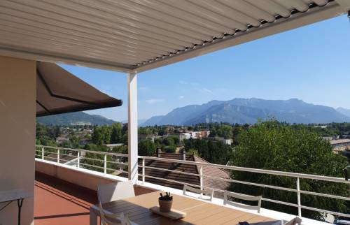 Les lames fermées créent une zone ombragée au-dessus de l’espace repas et protègent la terrasse du soleil direct.
