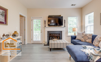 Rénovation salon moderne près de Dreux – Transformation élégante avec sol effet bois, cheminée blanche et canapé bleu cosy. Un intérieur lumineux et chaleureux.