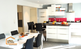 Cuisine ouverte moderne rénovée près d'Aix-en-Provence avec îlot central, grandes baies vitrées et espace repas convivial, pensée pour améliorer le confort et la circulation au quotidien.