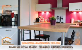 La cuisine rénovée dévoile une crédence rouge moderne, contrastant élégamment avec les meubles blancs et le plan de travail en bois clair, pour un espace à la fois pratique et chaleureux.