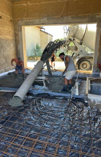 Coulage de la dalle béton dans la grange lors du gros œuvre du projet de rénovation à Voiron