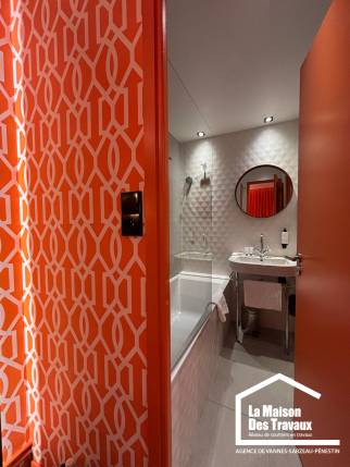 Pose d'un papier peint à motifs géométriques orange et blanc pour une chambre moderne.