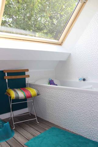 Baignoire installée dans les combles aménagés pour une salle de bain fonctionnelle