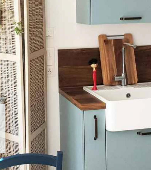 Rénovation de cuisine à Agen : Cuisine moderne avec façades bleu pastel, plan de travail en bois et évier farmhouse. Un projet signé La Maison Des Travaux Agen.