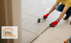 Sur cette image, on peut voir un artisan professionnel, équipé des outils appropriés, procéder à la pose des carreaux. 