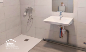 Salle de bain PMR rénovée à Castillonnès avec douche de plain-pied, lavabo suspendu et espace dégagé pour faciliter les déplacements.