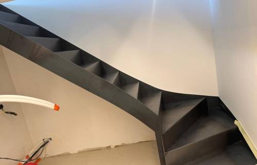 Pose de l’escalier métallique permettant l’accès à la mezzanine dans cette rénovation complète de grange.