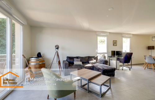 Un coin salon spacieux et chaleureux, avec des fenêtres laissant entrer une lumière naturelle généreuse.