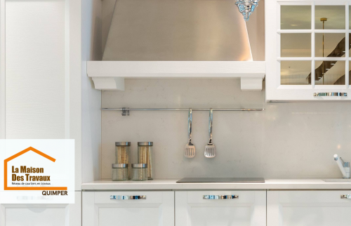 Rénovation de cuisine à Pont-l’Abbé : meubles blancs au style rustique moderne, crédence claire et hotte design pour une cuisine lumineuse et élégante.