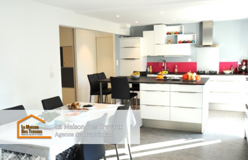 Vue d’ensemble de la cuisine rénovée avec un îlot central accueillant et une table à manger à proximité pour plus de convivialité.