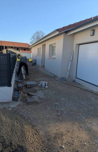 Travaux de préparation et pose des bordures en pavés pour une cour en béton désactivé à Saint-Cassien.