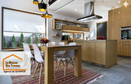 Une cuisine élégante en bois clair avec un îlot central, baignée de lumière naturelle grâce à de grandes fenêtres. 🍎✨