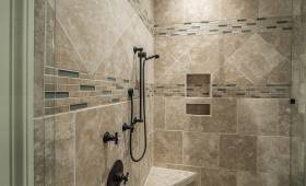 Zoom sur une douche avec carrelage en travertin posé en diagonale et frise décorative à Noyelles-Godault.