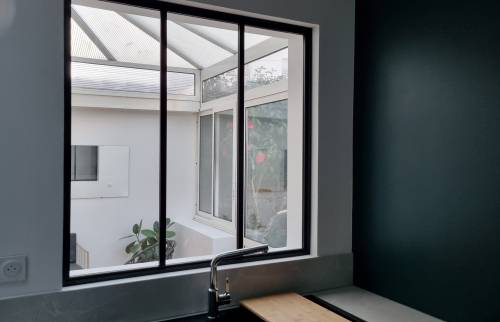 Véranda vue depuis agrandissement cuisine au travers verrière mi-hauteur (Meaux - 77)