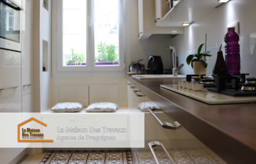 Les carreaux de ciment au sol et les éclairages intégrés sous les placards ajoutent une touche décorative et moderne à cette cuisine rénovée.