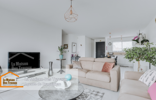 Un salon ouvert sur la cuisine, entièrement rénové avec des murs blancs éclatants et des finitions modernes. La décoration sobre et élégante met en valeur l'espace lumineux.