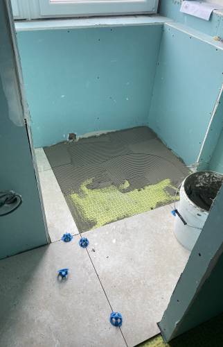 Pose du carrelage sur natte d'étanchéité prévue à cet effet 