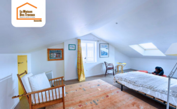 Chambre sous combles aménagée à Thyez 74300 avec mobilier bois, murs blancs, lumière naturelle et Velux – rénovation intérieure en Haute-Savoie.