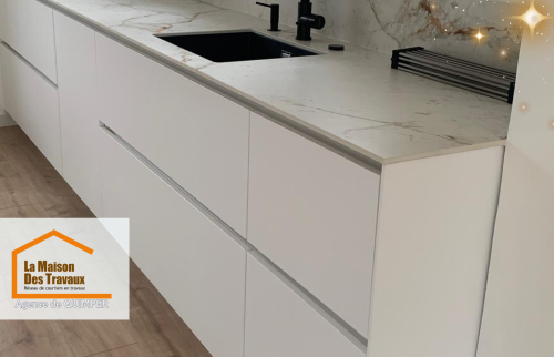 La cuisine toute en modernité avec un plan de travail en marbre veiné et un évier noir mat, alliant design et praticité.