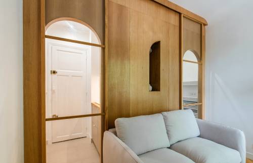 Espace de vie optimisé avec un canapé-lit et une paroi en bois clair