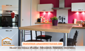 La cuisine rénovée dévoile une crédence rouge moderne, contrastant élégamment avec les meubles blancs et le plan de travail en bois clair, pour un espace à la fois pratique et chaleureux.