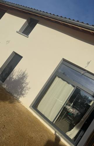 Façade rénovée avec enduit clair et menuiseries anthracite à Voiron