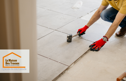 Sur cette image, on peut voir un artisan professionnel, équipé des outils appropriés, procéder à la pose des carreaux. 