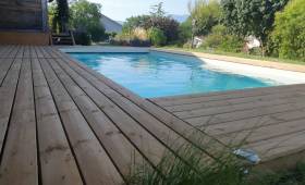 La nouvelle terrasse en bois offre un cadre chaleureux et confortable autour de la piscine.