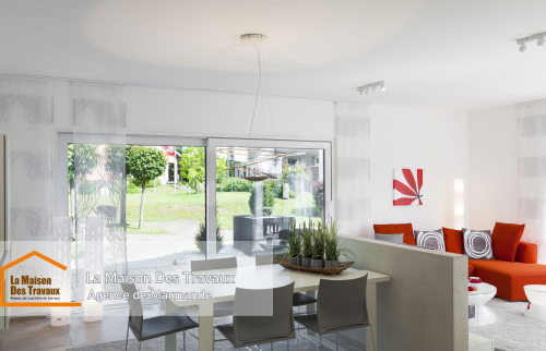 L'espace lumineux de la salle à manger avec de grandes baies vitrées, offrant une vue dégagée sur le jardin.