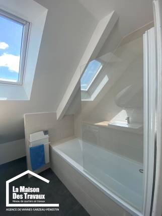 Aménagement d'une salle de bain lumineuse sous combles avec baignoire
